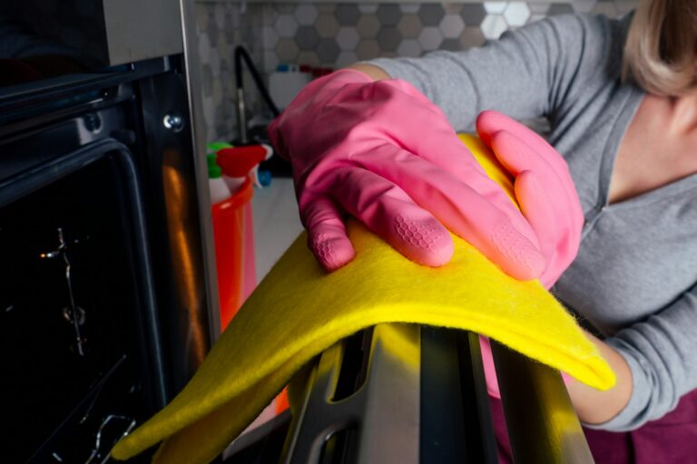 Young woman cleaning oven in the kitchen